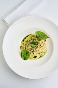 Whole roasted celeriac is elegantly plated with a rich tahini herb sauce and scattered tobiko, showcasing a unique culinary presentation ideal for a sophisticated meal