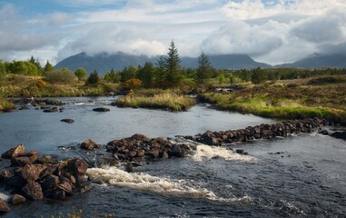 landscape scenery river stream, forest, mountains in the background at Derryclare, Connemara Ireland