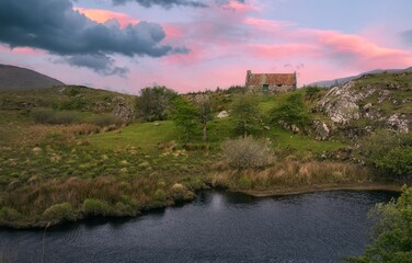 sunrise landscape scenery old rusty tin roof cottage on green hill Connemara, Ireland background