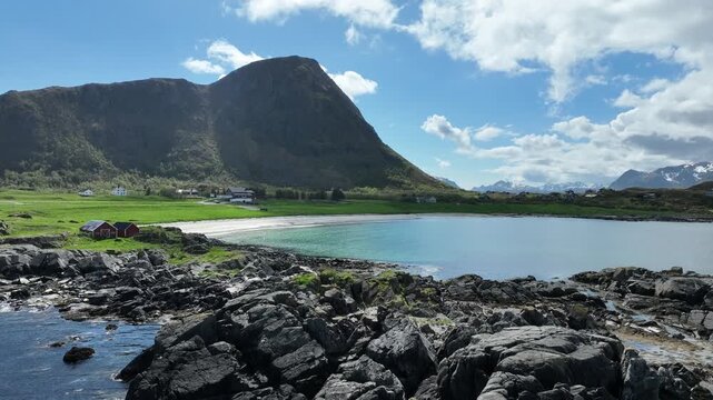 Low flight over rocky shore told Hov Beach on Gimsoy Island, Lofoten, Norway, Hoven Mountain in background.