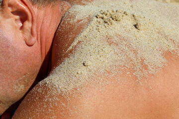 Fototapeta premium Sand on man’s tanned back at the beach