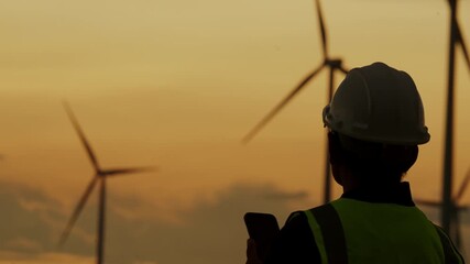 Silhouette of smart grid engineer holding mobile phone at wind farm. Concept of clean energy control, smart technology, and real-time renewable energy data. - Powered by Adobe