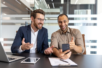 Businessmen having video call on smartphone in office