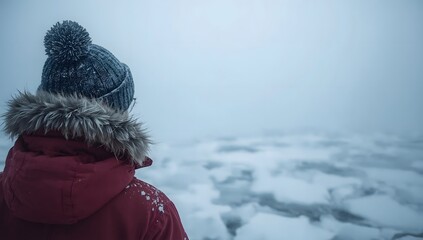 Person in winter coat looking out at a frozen icy landscape