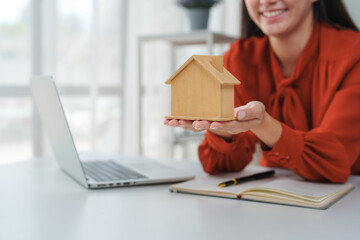 Real estate agent holding small wooden house in office
