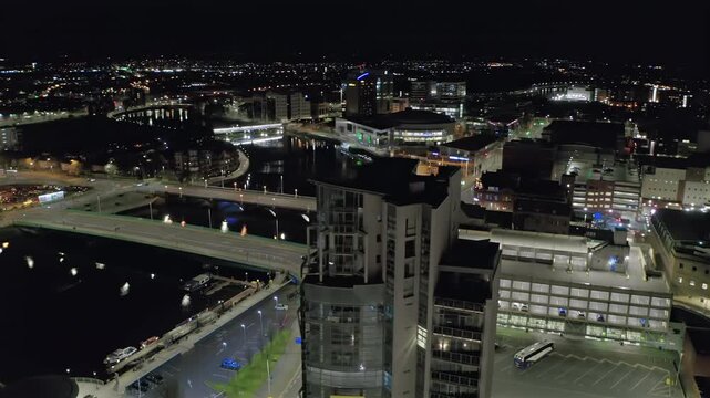 Aerial footage of calm Belfast City at night, featuring the River Lagan and illuminated architecture.