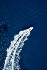 Aerial overhead view of a RIB Boat crossing the blue ocean in a curve with speed