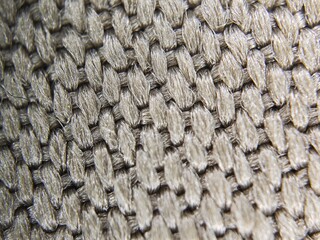 A detailed macro close-up of a woven metal fabric used for heat resistance. The intricate, interlocking pattern creates a unique abstract texture, perfect for industrial, technology