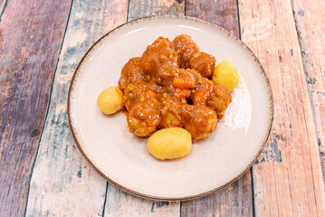 Lamb meatballs with a mint and red wine sauce, garnished with fresh mint and accompanied by couscous with toasted pine nuts