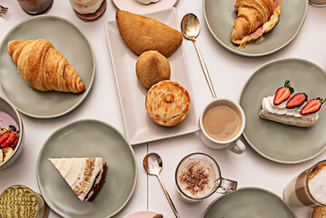 A central perspective of a table with fresh fruit tartlets, individual chocolate cakes, and French delicacies such as éclairs and profiteroles