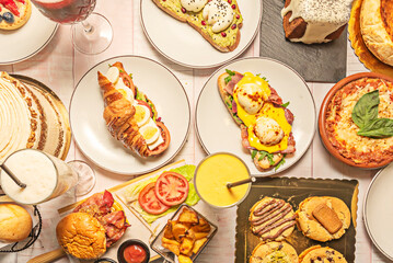A festive arrangement of decorated gingerbread cookies, chocolate houses, and red and white candy canes on a Christmas tablecloth