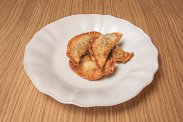 Chicken empanadas with saffron and almonds, fried in olive oil and garnished with black garlic powder and parsley