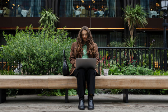 Businesswoman working outdoors on laptop in urban park setting