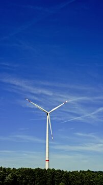 Wind turbines on a farm generating renewable electricity at an environmentally friendly power plant. Windmills against a blue sky.