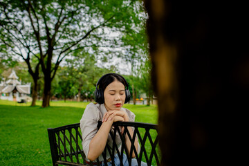 Happy woman sitting outdoors in nature under a tree, reading a book peacefully, enjoying summer relaxation, wellness, learning, and tranquility.
