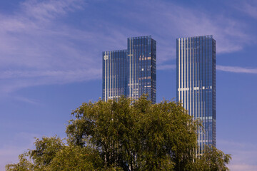 Fototapeta premium High-rise buildings and skyscrapers on a sunny summer day. Sunbeams and glare on the buildings