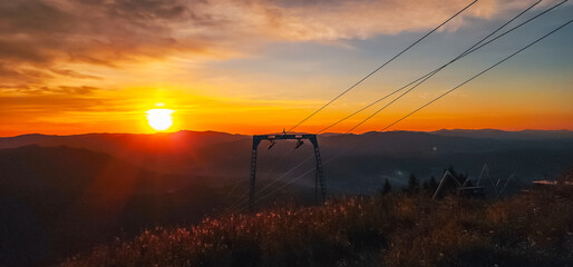 A breathtaking sunrise over a lush mountain range with vibrant wildflowers and dense forests,...