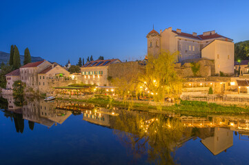 Fototapeta premium Charming Trebinje waterfront at dusk reflecting warm lights and iconic architecture