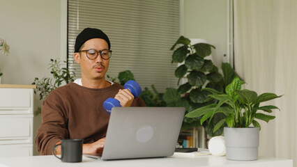Asian man multitasking workout and work at home.