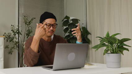 Asian man attending an online business meeting while working from home.