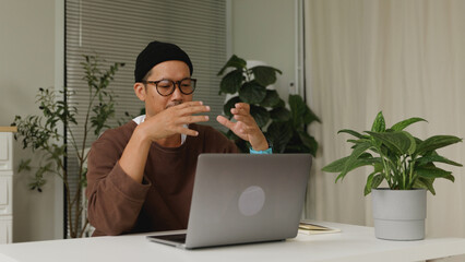 Asian man attending an online business meeting while working from home.