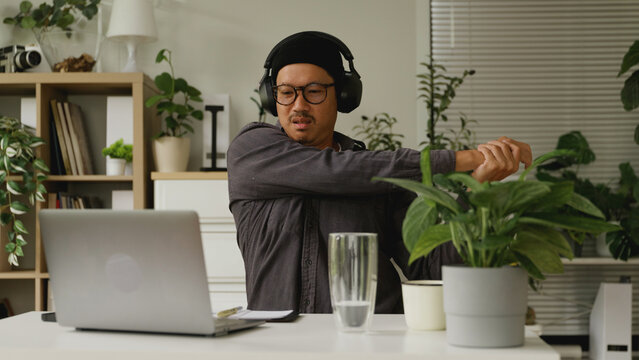 Asian man is stretching his body after working at home.