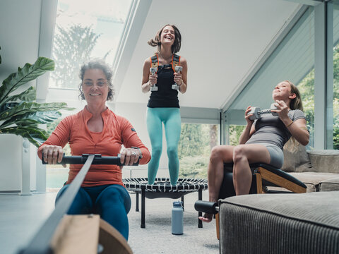 Family exercising together at home with weights and rowing machine