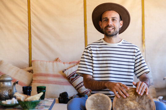 Person playing bongo in haima interior of Morocco Sahara desert camp