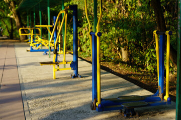 Fototapeta premium Outdoor fitness equipment at a park in the early morning sunlight surrounded by greenery