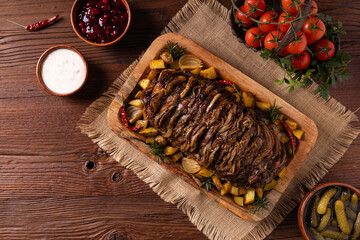 Roasted whole pork neck. Stuffed with onion slices. Served with baked potatoes.