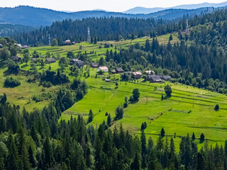 Obraz premium A stunning view of a mountain village nestled among rolling hills and wildflowers, perfect for travel promotions, eco-tourism, and nature retreats