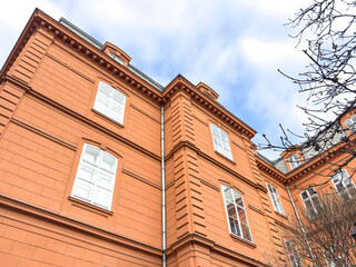 brick building with white framed windows, ornate cornice in Europe