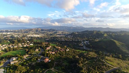Fototapeta premium High-angle view of a valley with suburban homes, hills, and clouds