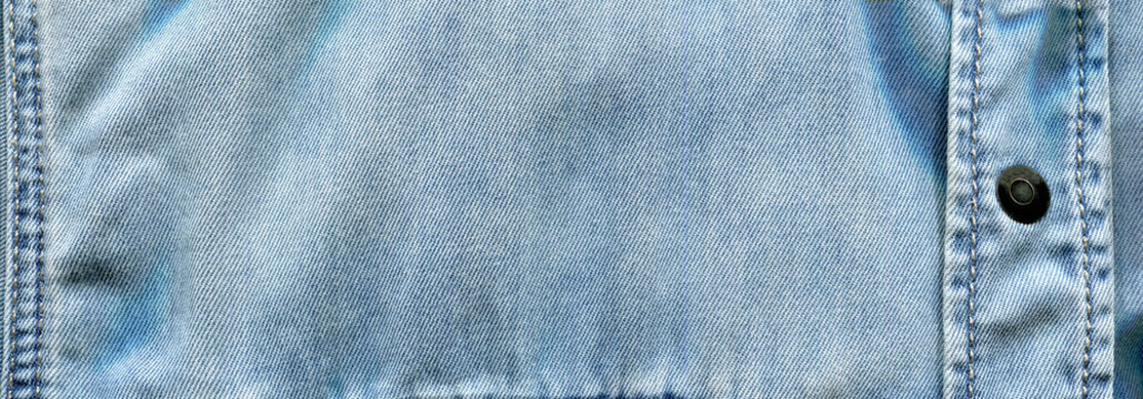 Stitched light blue denim cotton shirt, pocket and button detail, jeans fabric texture background