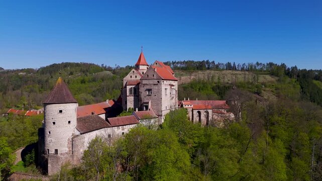 Aerial drone panning slowly around the majestic Pernstein Castle, highlighting its Gothic and Renaissance architecture perched high on a massive rock above Nedvedice, Czechia.