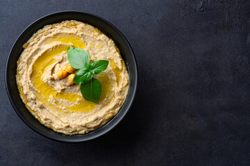 A traditional dish or appetizer hummus or baba ghanoush on black  background