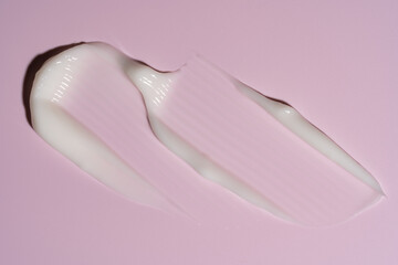 White cosmetic cream texture, skincare lotion swatch on pink background. Face creme, body moisturizer, hair conditioner smear smudge stroke. Creamy beauty product closeup