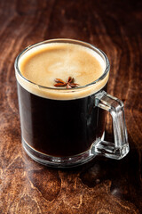 Glass mug of dark beer with creamy foam head on rustic wooden table, on black background. Refreshing cold drink in classic pub setting, perfect for beverage-themed stock use.