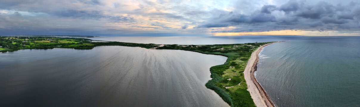 Aerial view of Block Island's dramatic coastline, where dark waters meet a narrow strip of sandy beach, and the verdant land stretches out, New Shoreham, Rhode Island, United States.