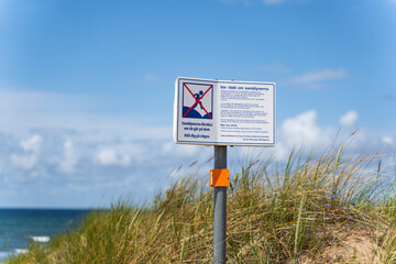 A Beach Sign Displaying a Cautionary Message Located Near the Ocean Shoreline Area