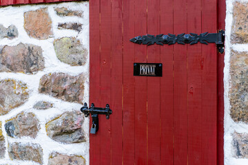 An inviting and charming red door adorned with a distinctive private sign on a weathered stone wall