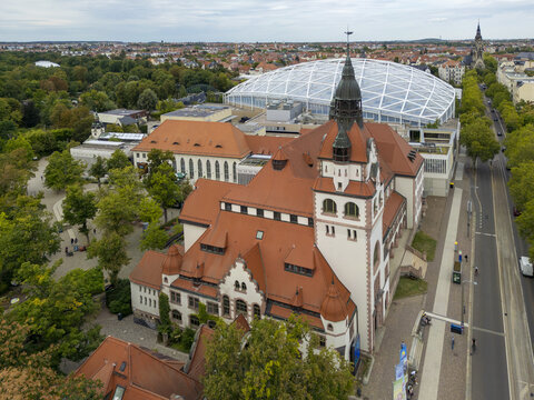 Aerial view of the imposing red-roofed Grassi Museum complex stands in stark contrast to the modern glass dome of the Leipzig Zoo, Leipzig, Saxony, Germany.