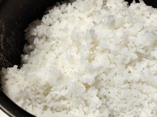 炊飯器で炊かれたばかりの白米が湯気を立てて輝いています。ふっくらと炊きあがり美味しそうな雰囲気を伝えています。