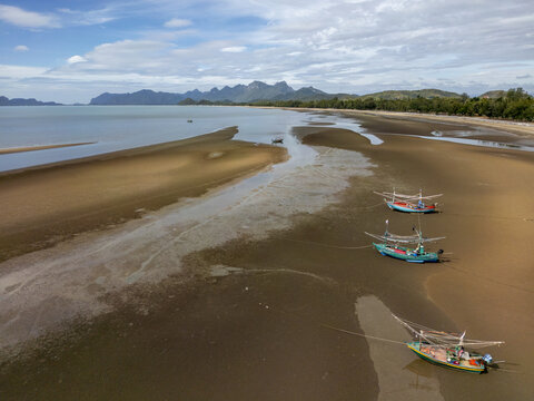 Aerial view of fishing boats resting on the sandy beach, contrasted against the calm sea and distant mountains, Tambon Sam Roi Yot, Chang Wat Prachuap Khiri Khan, Thailand.