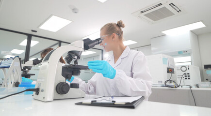 Scientist examining samples under microscope in a modern laboratory setting