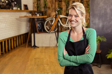 Female barista in black apron standing in café with espresso machine and bicycle, copy space