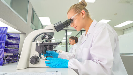 Scientist examines samples under microscope in modern laboratory setting