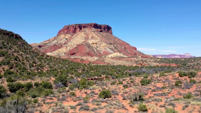 Red mesa rises over desert scrub under a clear sky