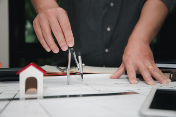 Close up of architect hand using compass drawing house plan on blueprint, architecture and...