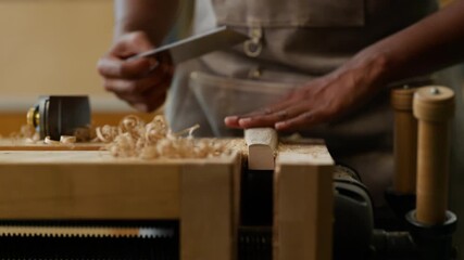 A skilled artisan shapes wood using a hand plane in a sunlit workshop, surrounded by shavings and tools, emphasizing the craft of woodworking.